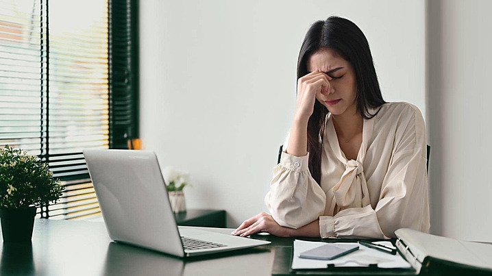 A woman sitting at a desk with a laptop feeling stressed and trying to fix brain fog in 2026