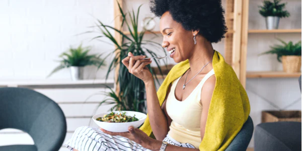 A feemale eating a healthy salad bowl to support metabolic flexibility and overall biological health optimization