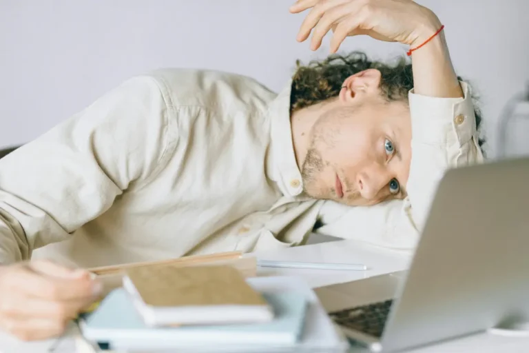 A frustrated and exhausted remote worker leaning on his hand at a desk staring blankly past his laptop This image perfectly captures the mental fatigue and cognitive overwhelm associated with neural burnout highlighting the need for a mental refresh to regain peak focus